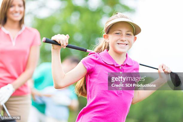 kleines mädchen mit der ganzen familie golf spielen im country club golfplatz - mini golf stock-fotos und bilder