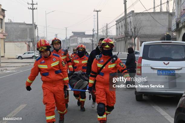 Rescuers carry an injured woman after a 6.2-magnitude earthquake on December 19, 2023 in Jishishan Bonan, Dongxiang and Salar Autonomous County,...