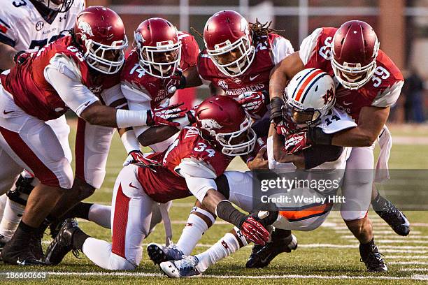 Nick Marshall of the Auburn Tigers is tackled by a group of defenders during a game against the Arkansas Razorbacks at Razorback Stadium on November...