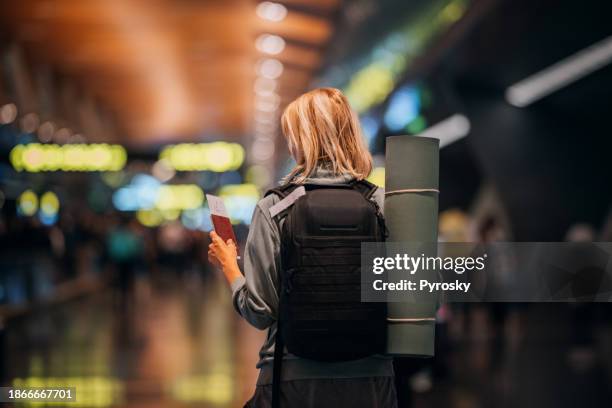 a woman at the airport holding a passport with a boarding pass - mat stock pictures, royalty-free photos & images