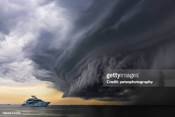 luxusyacht unter einer beängstigend aussehenden tropischen "schelfwolke" - taifun stock-fotos und bilder