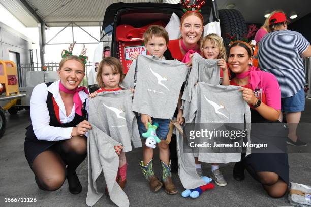 Qantas cabin crew pose for a photo with three children as they gift them special Qantas pyjamas at Miles Airport on December 19, 2023 in Miles,...