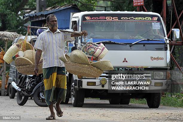 Sri Lankan vendor carries woven reed bags and baskets for sale on a street in Maharagama, a suburb of Colombo on November 3, 2013. Sri Lanka's...