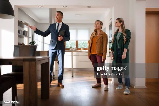 real estate agent showing house to customers - long coat stock pictures, royalty-free photos & images