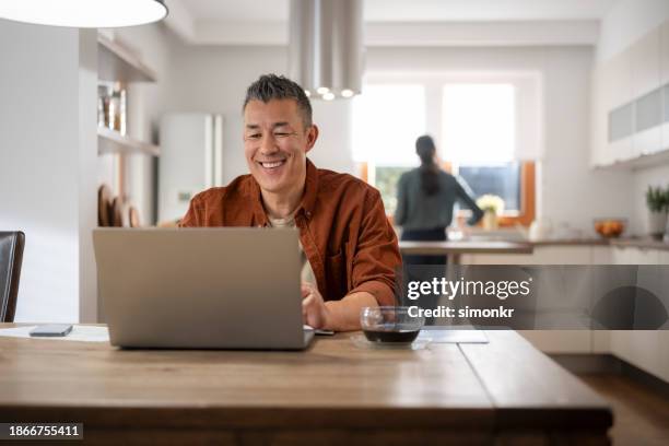 mature man using laptop - person facing forward smiling stock pictures, royalty-free photos & images