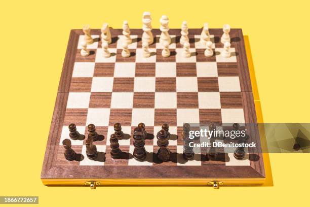 classic wooden chess board with all the pieces placed, on yellow background. concept of game, sport, battle, pawn, rook, bishop, knight, queen and king. - scacchiera foto e immagini stock