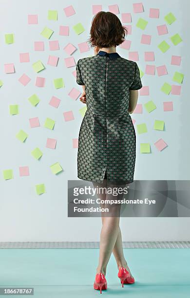 woman looking at sticky notes on board - vista posteriore foto e immagini stock