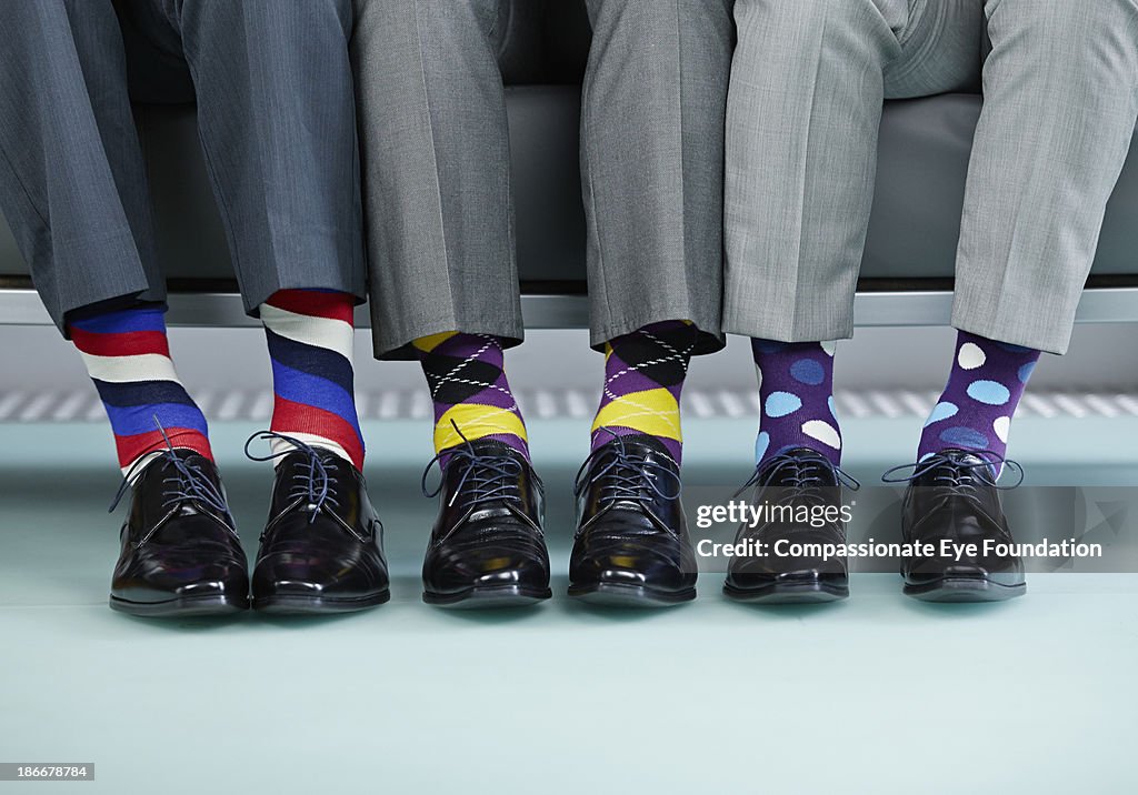 Men sitting on bench wearing colourful socks