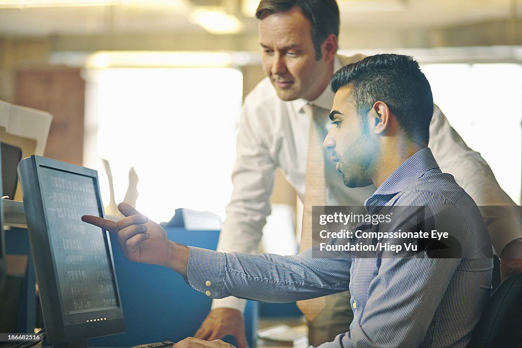 Man showing colleague work on computer screen