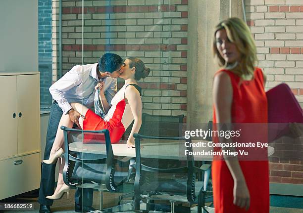 woman walking past couple kissing in office - walking past office wall stock pictures, royalty-free photos & images