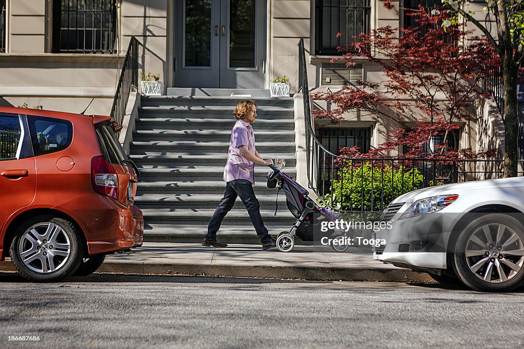 Father walking baby in stroller in NYC