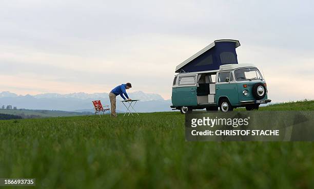 Volkswagen Kombi owner Wanja Fuhrmann sets up a camping table next to his Volkswagen T2 camper van built in the year 1975 near Landsberg, southern...