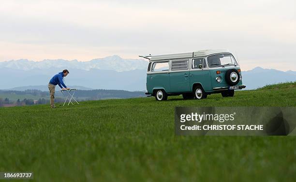 Volkswagen Kombi owner Wanja Fuhrmann sets up a camping table next to his Volkswagen T2 camper van built in the year 1975 near Landsberg, southern...