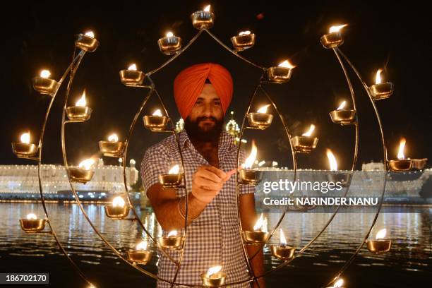 An Indian Sikh devotee lights candles at the illuminated Sikhism's holiest shrine Golden Temple in Amritsar on November 3 on the ocassion of Bandi...