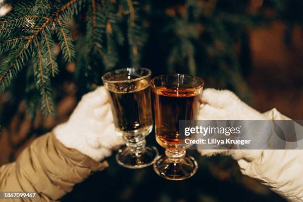 woman at the christmas market holding mulled wine (fire tongs punch) in her hands. - mulled wine stock pictures, royalty-free photos & images