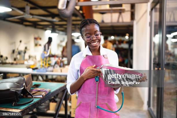 young female tailor black ethnicity showing modern leather bag she made - fashion designer stock pictures, royalty-free photos & images