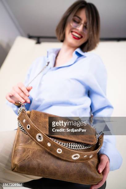 kaukasisches weibliches modemodell, das eine braune ledertasche trägt - ledertasche stock-fotos und bilder