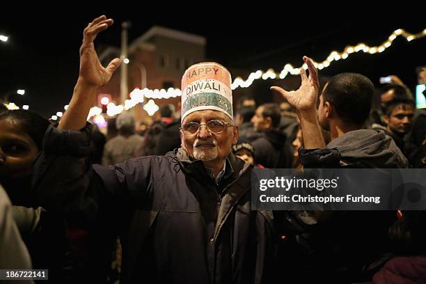 Man wearing a 'Happy Diwali' hat dances in the street as thousands celebrate the Hindu festival of Diwali on November 3, 2013 in Leicester, United...