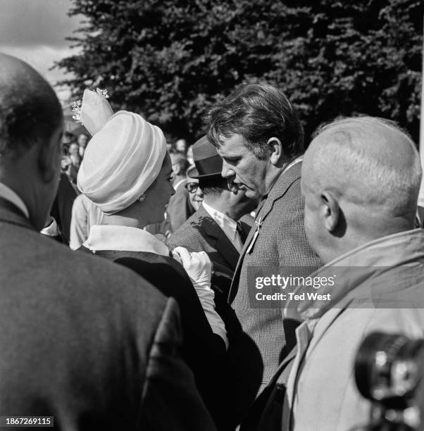 British actress Elizabeth Taylor and British actor Richard Burton in conversation among a group of people attending the Variety Club of Great Britain...