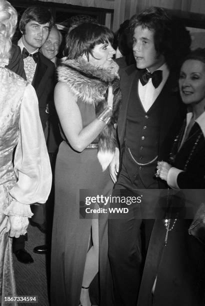Actress and singer Liza Minnelli, wearing a coffee jersey halter dress by Halston and a silver fox fur, with Desi Arnaz Jr. Wearing a tuxedo at the...