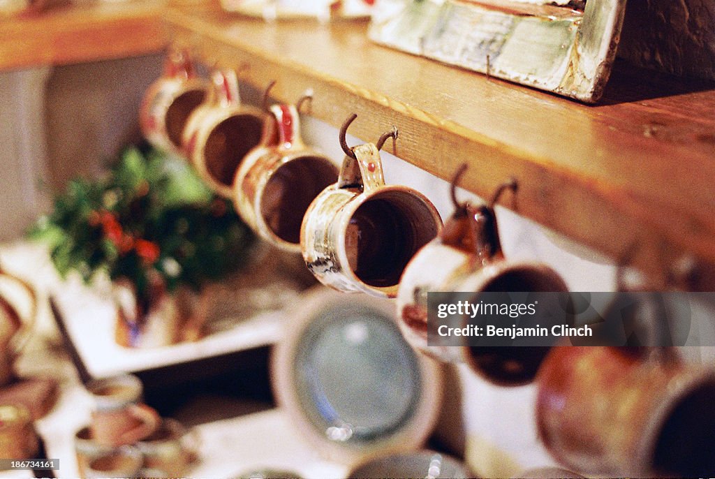 Handmade pottery mugs hanging on a shelf