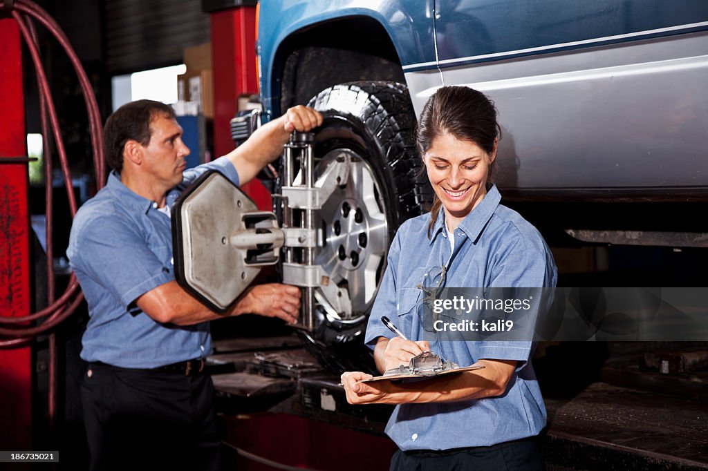 Car mechanics performing wheel alignment