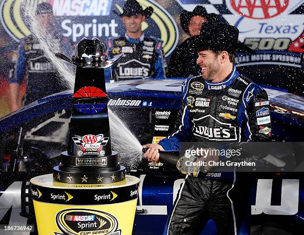 Jimmie Johnson, driver of the Lowe's Chevrolet, celebrates in victory lane with champagne after winning the NASCAR Sprint Cup Series AAA Texas 500 at...