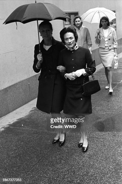 Outtake; The Duchess of Windsor huddling under an umbrella with Francoise de la Renta, trying to protect her navy Dior suit after a luncheon at...