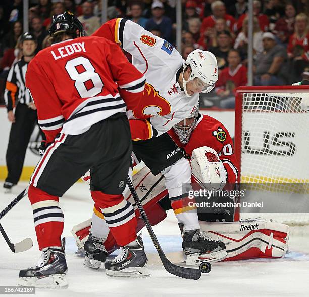 Joe Colborne of the Calgary Flames tries to get off a shot between Nick Leddy and Corey Crawford of the Chicago Blackhawks at the United Center on...