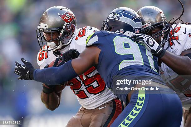 Running back Mike James of the Tampa Bay Buccaneers rushes against defensive end Chris Clemons of the Seattle Seahawks at CenturyLink Field on...