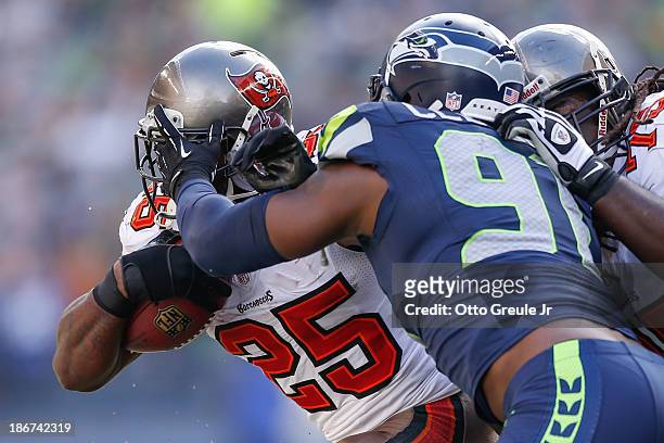 Running back Mike James of the Tampa Bay Buccaneers rushes against defensive end Chris Clemons of the Seattle Seahawks at CenturyLink Field on...