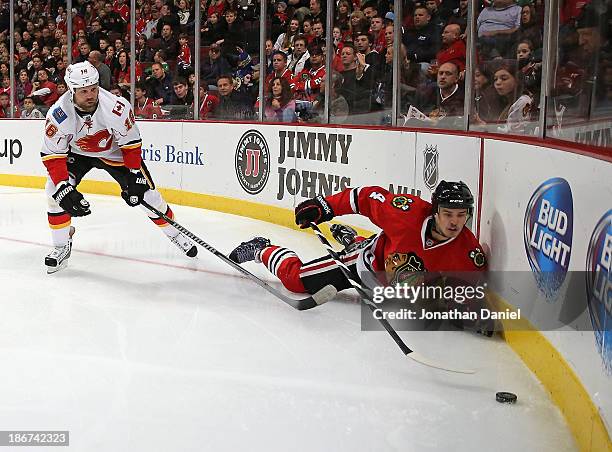Niklas Hjalmarsson of the Chicago Blackhawks tries to reach the puck after being knocked down by Brian McGrattan of the Calgary Flames at the United...