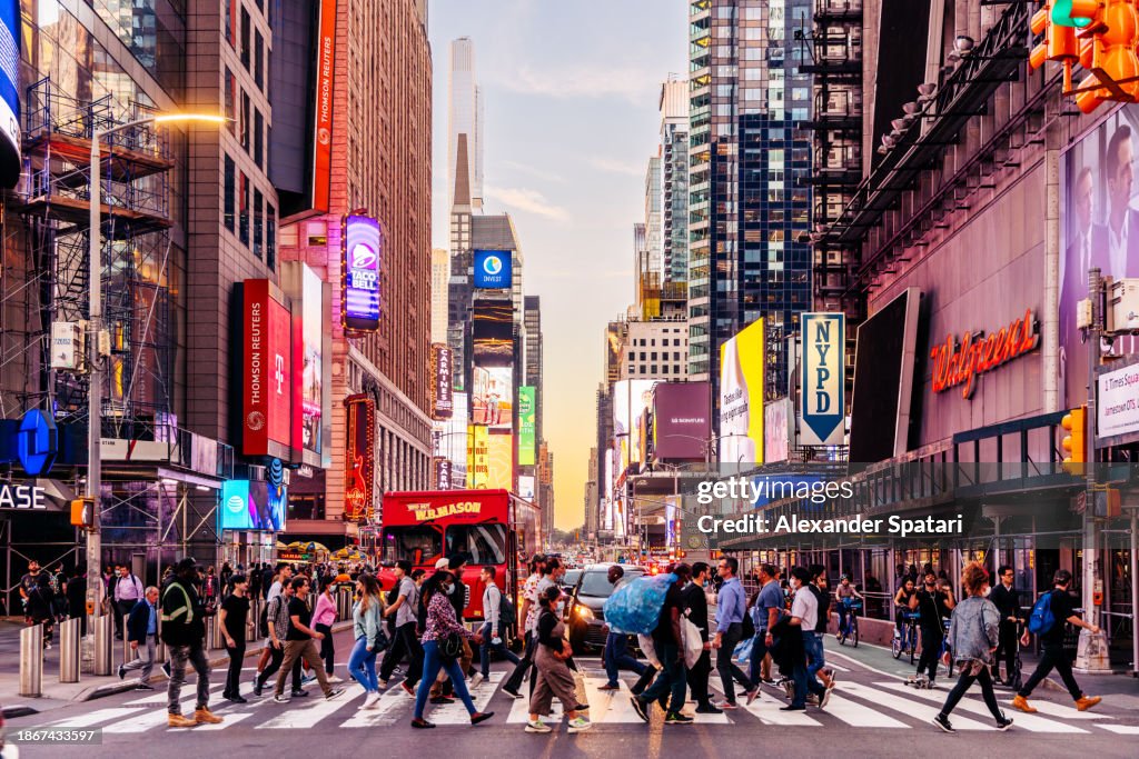 People crossing the street near Times Square at sunset, New York City, USA