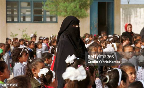 Palestinian female teacher stands among students in Khan Younis UNRWA elementary D school, on December 15, 2001.