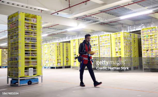 An Amazon employee checks the robotic warehouse at Amazon's Robotic Fulfillment Centre on December 19, 2023 in Sutton Coldfield, England. Launched in...