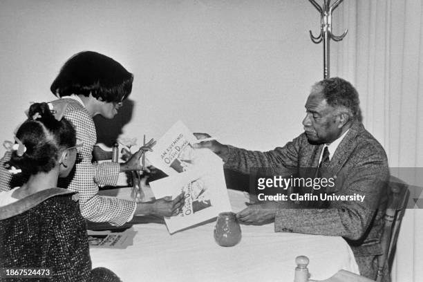 Ossie Davis sign autographs for fans at a event at Claflin University. Ossie Davis was a American actor, director, writer, and activist. He was...
