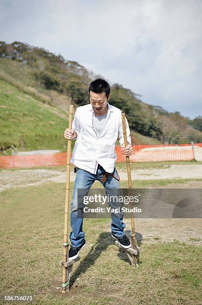 man playing on stilts in the square - stilt stock pictures, royalty-free photos & images