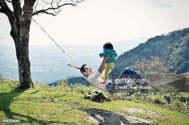 father and daughter riding a hammock - middlebare afstand stockfoto's en -beelden