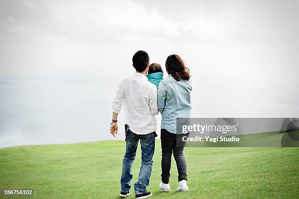parents holding daughter in the grass - couple standing full length stock pictures, royalty-free photos & images