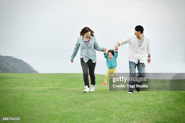 parents lifting daughter mid air - familia de dos generaciones fotografías e imágenes de stock