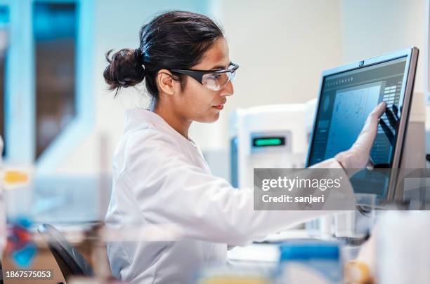 female scientist working in the lab, using computer - indian education health science and technology stockfoto's en -beelden