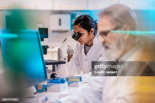 female scientist working in the lab, using microscope - evolution stock pictures, royalty-free photos & images