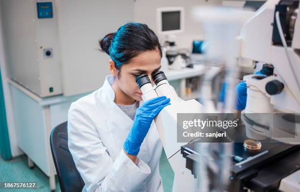 female scientist working in the lab, using microscope - microscoop stockfoto's en -beelden