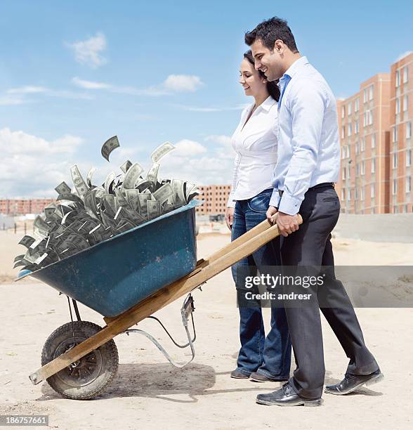 rich couple carrying money - wheelbarrow stock pictures, royalty-free photos & images