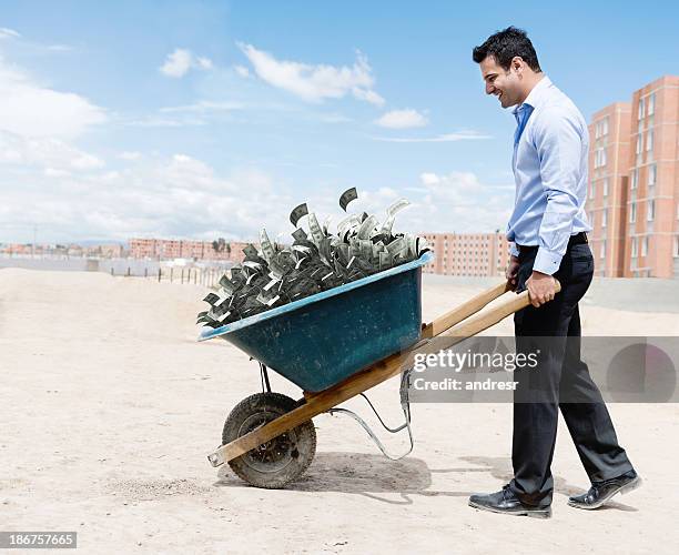 rich man carrying money - kruiwagen stockfoto's en -beelden