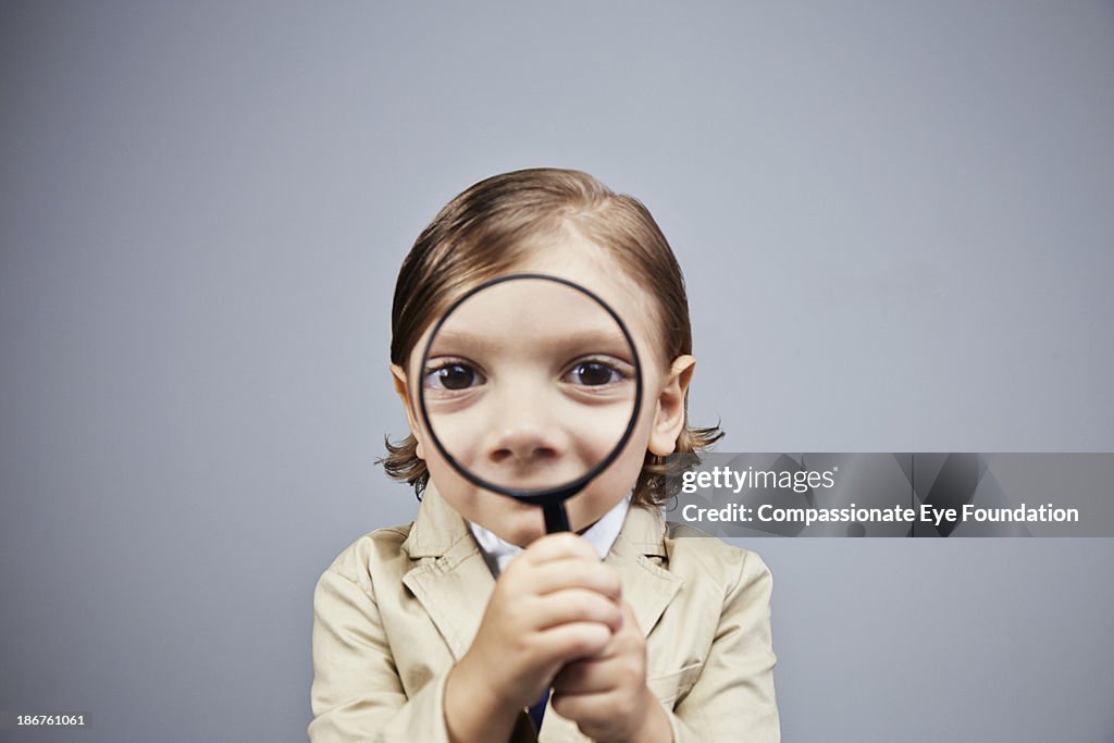 Boy (3-5) looking through magnifying glass