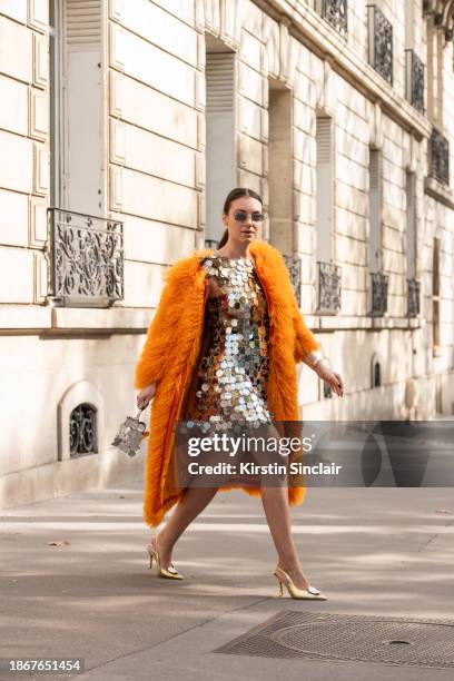 Aandrea Cristea wears a Lisou coat, Paco Rabanne dress and bag, silver sunglasses and Malone Souliers shoes outside the Rabanne show during the...