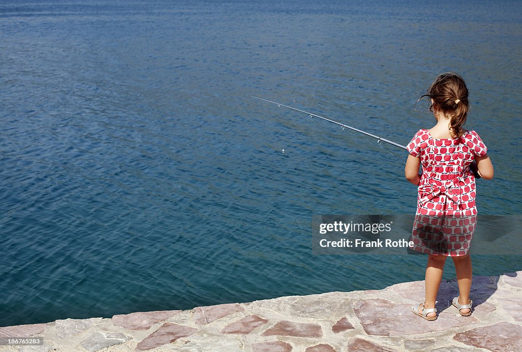 Little girl fishes in the sea