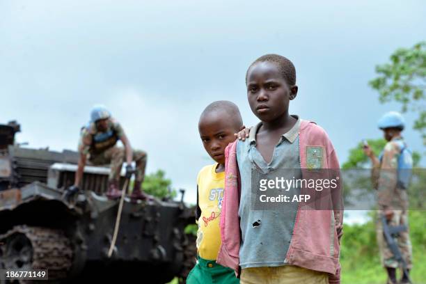 Children stand beside a burnt out tank, abandoned by M23 rebels on November 3, 2013 as UN forces patrol in Kibumba. Democratic Republic of Congo's...
