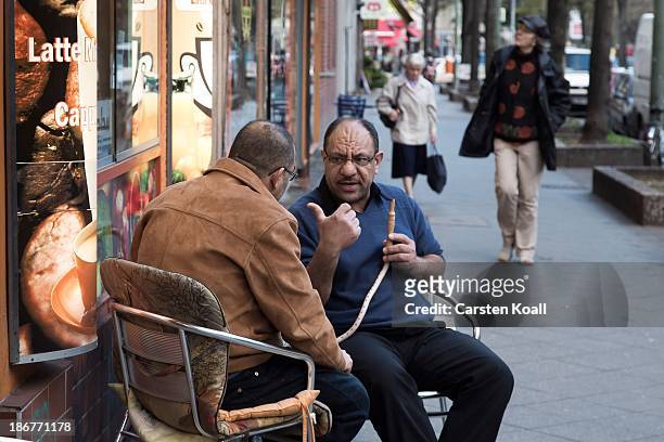 El Mohamed smokes a hookah pipe as he talks with native Palestinian Yaser A Rabah in front of a bar at Sonnenallee in Neukoelln district on October...